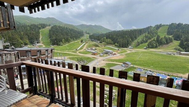 A balcony with a view of a mountainous landscape, including a ski resort and a road. - Studio with Balcony, Equipped Kitchen, Wi-Fi in Le Lioran (Le Lioran)