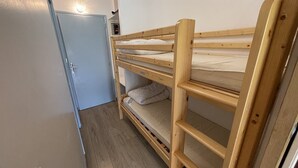 A compact room with a bunk bed, a door, and a small shelf. - Studio with Balcony, Equipped Kitchen, Wi-Fi in Le Lioran (Le Lioran)