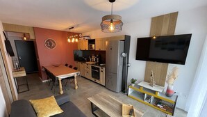 A modern apartment with a living room, dining area, kitchen, and a TV mounted on the wall. - Cozy New 2-BR Apartment with Large Balcony, Close to Chairlift (Le Lioran)