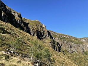 A mountainous landscape with rocky cliffs and sparse vegetation. - Cozy Studio for 4, South-Facing Balcony, Heart of Ski Resort (Le Lioran)