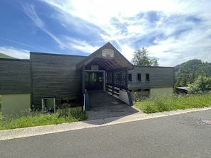 A lodge with a covered entrance, a sign indicating it is a residence and dance hall, and a view of the surrounding forest.