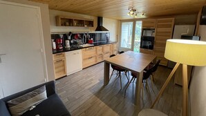 A compact kitchen with wooden cabinets, a dining table, and a sofa. - Charming duplex near slopes with balcony and parking (Saint-Jacques-des-Blats)