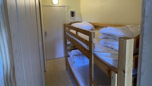 A bunk bed room with a door, a light fixture, and a small cabinet.