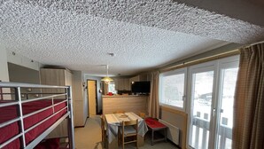 A compact room with bunk beds, a small kitchen, a dining area, and large windows. - Cozy studio at the slopes, Le Lioran (Le Lioran)