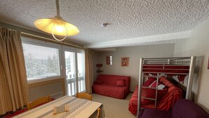 A compact room with a dining table, a bunk bed, and a sofa. - Cozy studio at the slopes, Le Lioran (Le Lioran)