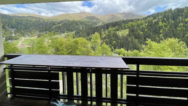 A balcony with a table and a view of a mountainous landscape.