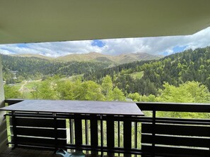 A balcony with a table and a view of a mountainous landscape.