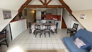 A compact living space with a dining area, kitchenette, and a blue sofa.
