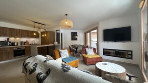 A modern living room with a sofa, a fireplace, a television, and a dining area. - Apartment Vars, 3 bedrooms, 8 persons (Vars)