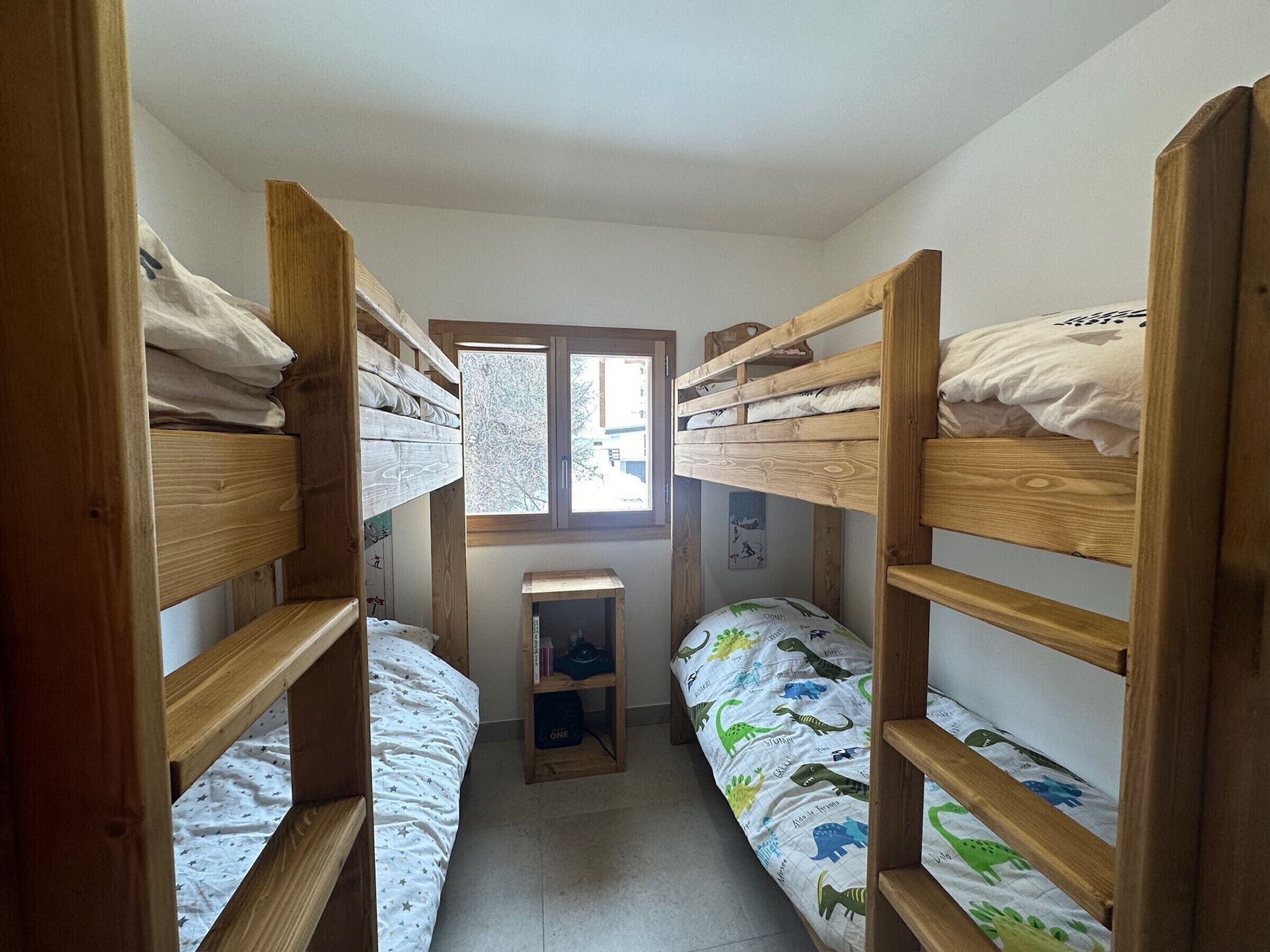 Um quarto pequeno com beliches e uma janela.