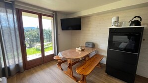 A modern kitchen with a wooden table and bench, a black oven, and a flat-screen TV mounted on the wall. - Renovated 2-bedroom apartment with terrace in Les Angles (Les Angles)