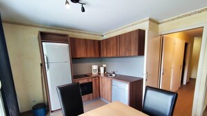 A compact kitchen with wooden cabinets, a refrigerator, a sink, and a dining table with chairs. - 3-room apartment in Isola 2000 center, parking, near slopes (Isola 2000)