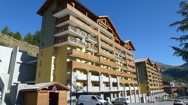 A multi-story hotel with balconies, a parking area, and a mountainous backdrop. - 3-room apartment in Isola 2000 center, parking, near slopes (Isola 2000)