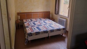 A bedroom with a bed, a nightstand, a window, and a door. - 3-room apartment in Isola 2000 center, parking, near slopes (Isola 2000)