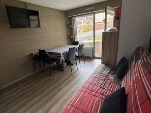 Cozy living space with a dining area and seating area, featuring a table, chairs, sofa, and television.