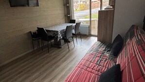 Une pièce comprenant une table et des chaises, un canapé et une porte-fenêtre coulissante donnant sur un balcon.