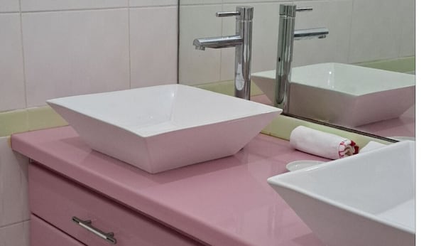 A bathroom with two white sinks, a pink vanity, and a mirror above the sinks.