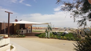 Een strandresort met een overdekte zitplek, een zwembad en strandparasols.