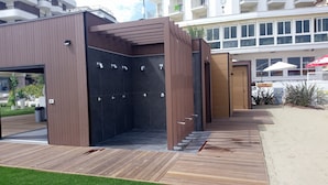 Een moderne buitendouche met een houten terras en een metalen deur.