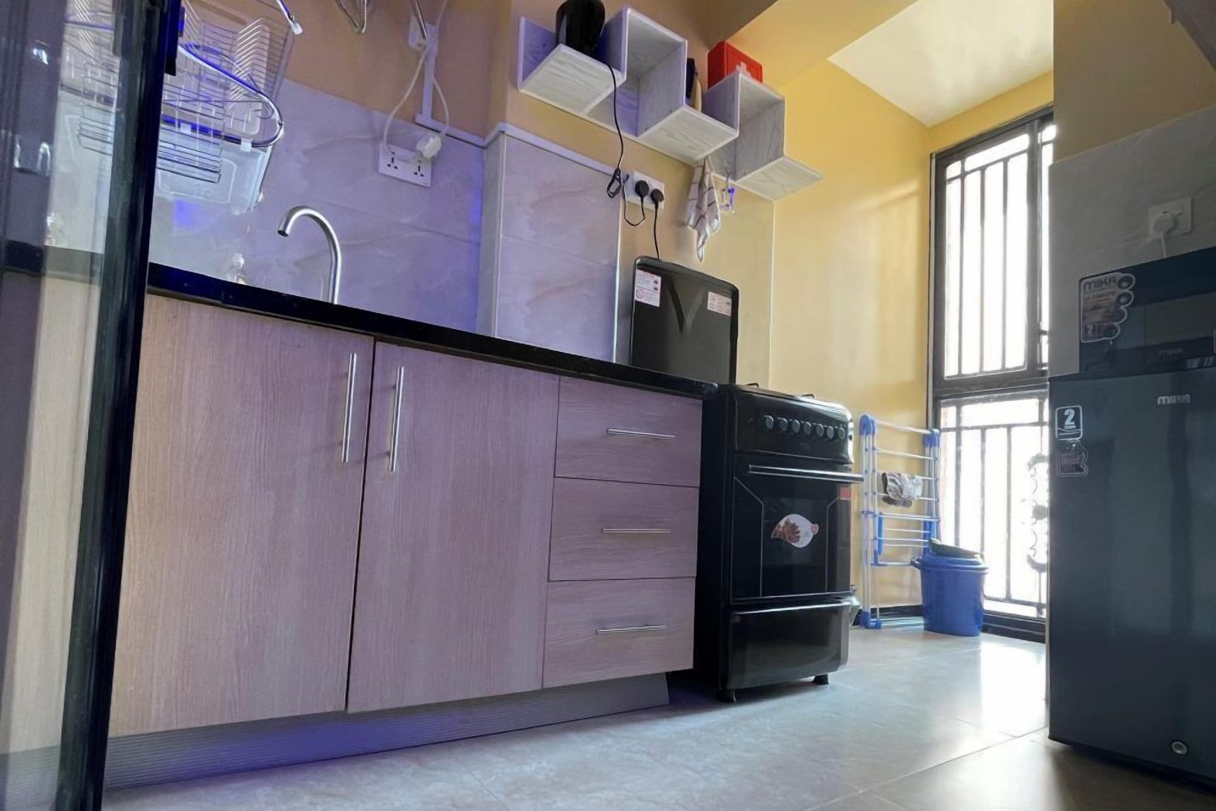 A kitchen with a built-in oven, a refrigerator, and a sink. There are cabinets and a countertop.