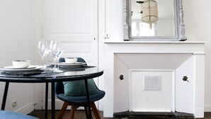 A dining area with a round table set for two, a chair, and a white door in the background. - Large studio apartment in the heart of Angers - 2 people (Angers)