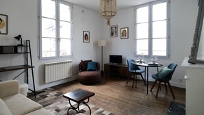 A living room with a sofa, a coffee table, a TV, and a dining area with chairs and a table. - Large studio apartment in the heart of Angers - 2 people (Angers)