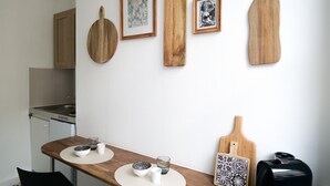 A kitchen with a wooden table, framed pictures, and a toaster. - Large studio apartment in the heart of Angers - 2 people (Angers)