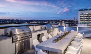 Eine Terrass mit Grill und Sitzgelegenheit mit Blick auf eine Stadtlandschaft.