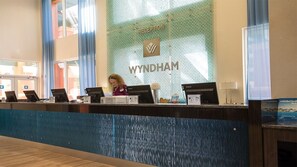 A reception desk with computers, a receptionist, and a reception area with a large wall displaying 'RECEPTION' and 'WYNDHAM'.