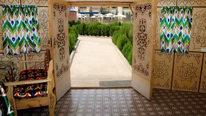 A doorway leading to a garden with patterned curtains and a tiled floor. - Gumbaz Eco SPA Hotel (Samarkand)