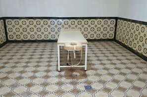 A corner room with patterned floor tiles and a small table with a cushion. - Gumbaz Eco SPA Hotel (Samarkand)