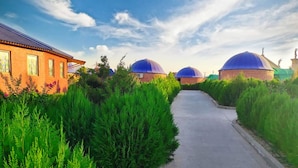 A pathway leading to a building with a brick facade and a blue dome structure. - Gumbaz Eco SPA Hotel (Samarkand)
