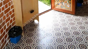 A room with a patterned floor, a wooden door with a decorative glass panel, and a brick wall with a small picture. - Gumbaz Eco SPA Hotel (Samarkand)
