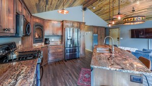 Une cuisine moderne avec des meubles en bois, des appareils en acier inoxydable et un îlot central doté d’un comptoir en granit.