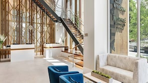 A modern lobby with a staircase, reception desk, and seating area.