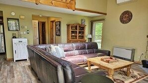 A living room with a leather sofa, a wooden coffee table, and a patterned rug.