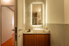 Un baño con un lavabo redondo, un espejo y armarios de madera.