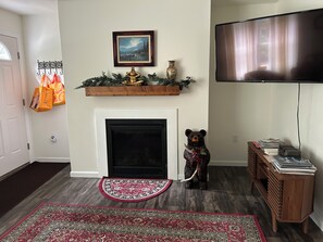 A living room with a fireplace, a mounted picture, a television, and a decorative bear statue.