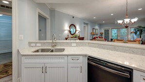 Una cocina moderna con una isla grande, armarios blancos y un lavavajillas integrado.