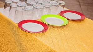 A table with clear glass jars and colored plates on a patterned tablecloth.