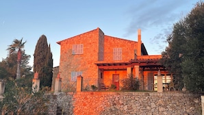 Un edificio in pietra su due piani con un muro in pietra e un pergolato in legno.