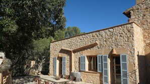 A stone building with shutters, a table, and chairs outside. - Quiet vacation home in the southeast of Mallorca (Manacor)