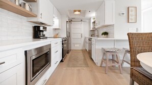 Een moderne keuken met witte kasten, roestvrijstalen apparatuur en een houten vloer.