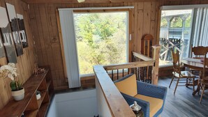 Un intérieur en bois avec un balcon, un coin repas et un escalier.
