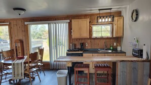 Une cuisine avec des meubles de rangement en bois, un îlot central, des tabourets de bar, une machine à café et un grille-pain.