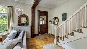 Un corridoio ben illuminato con una scala in legno, un grande specchio e una porta decorata con un festone.