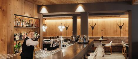 A bar area with wooden walls, a bar counter, and seating.