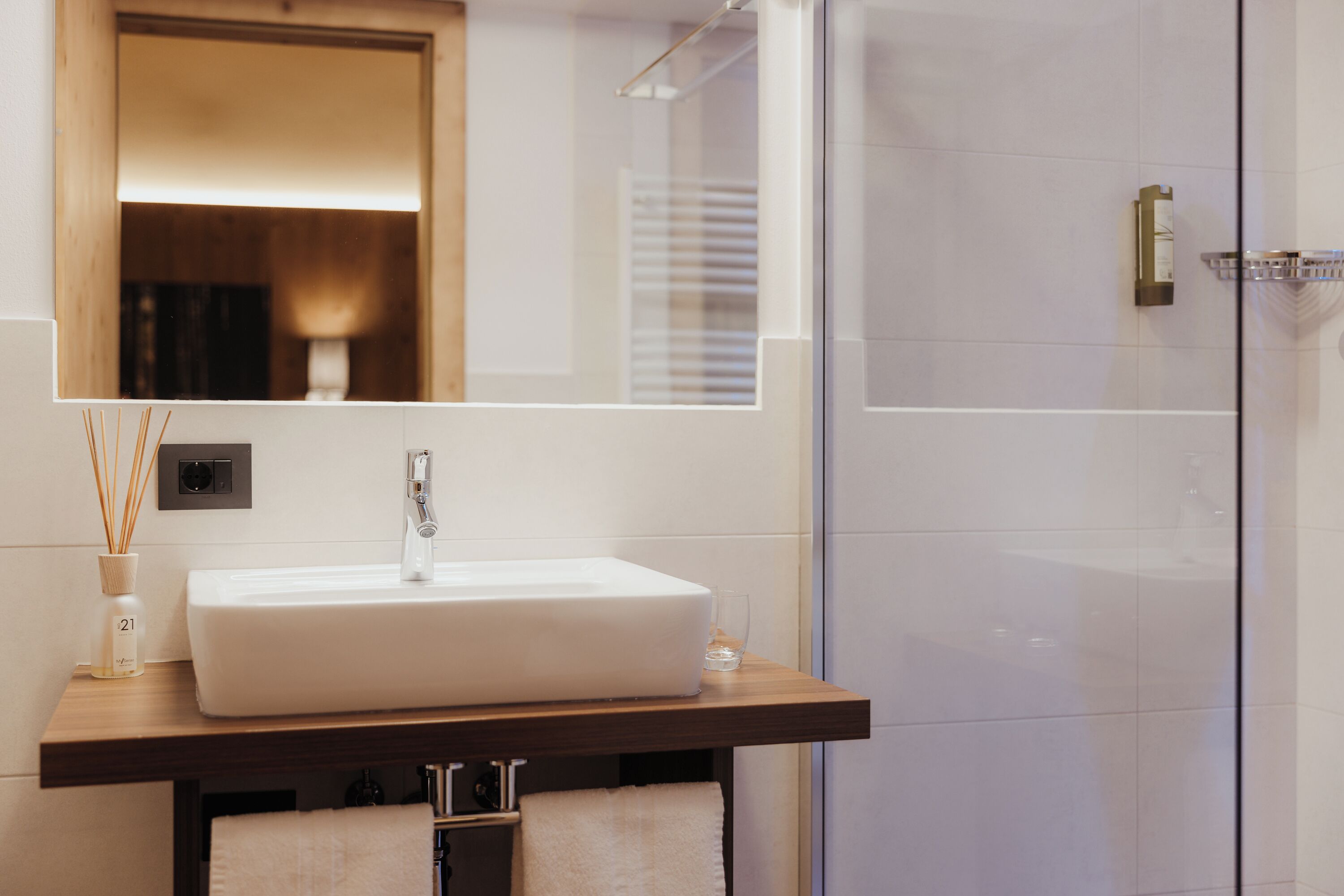 A bathroom with a white sink, a mirror, and a glass shower enclosure.