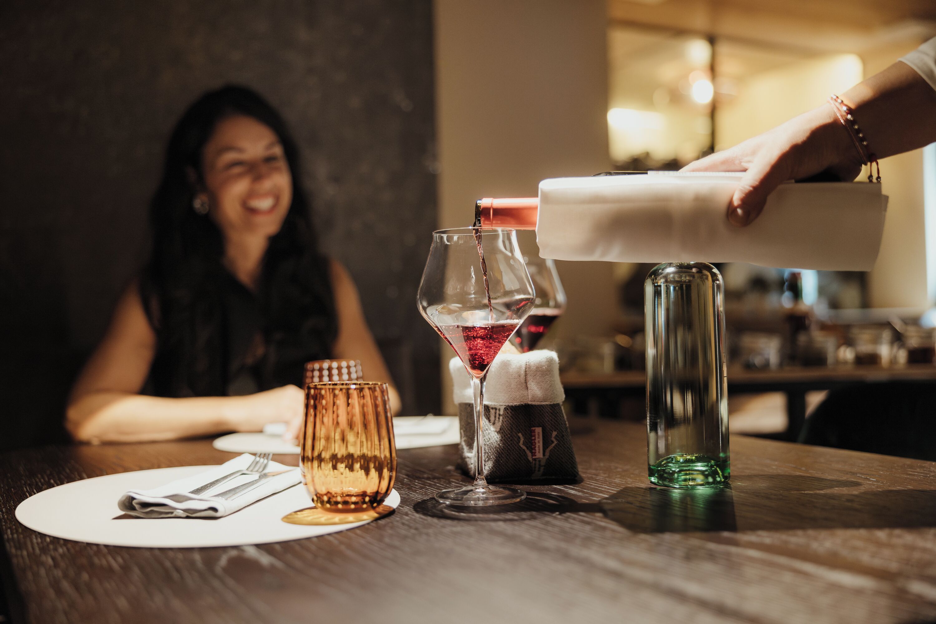 Une table à manger avec un verre à vin, une bouteille et une serviette.