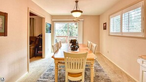 A dining area with a wooden table and chairs, a ceiling fan, and a large window with blinds. - Skyridge Cabin at Pine Mountain Lake (Groveland)